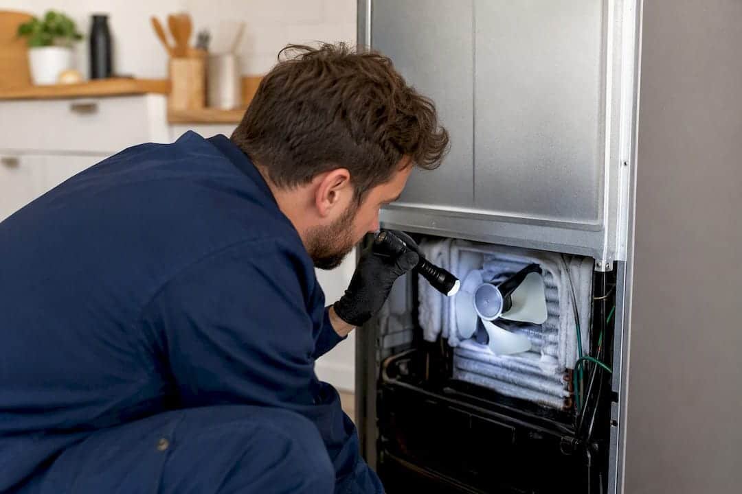 Hand inspecting refrigerator evaporator fan