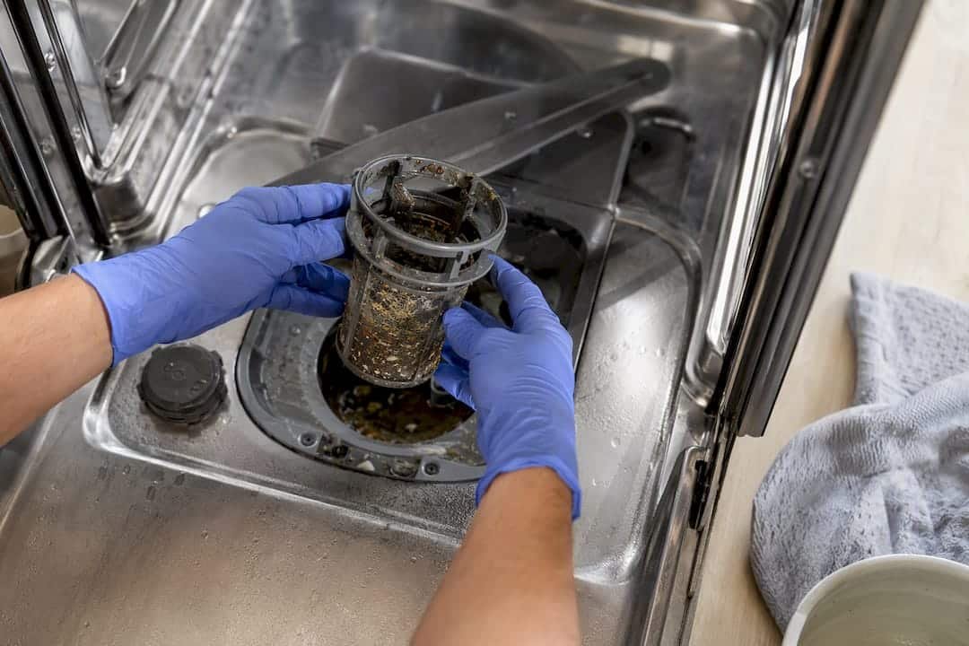 Hands removing dishwasher filter for cleaning